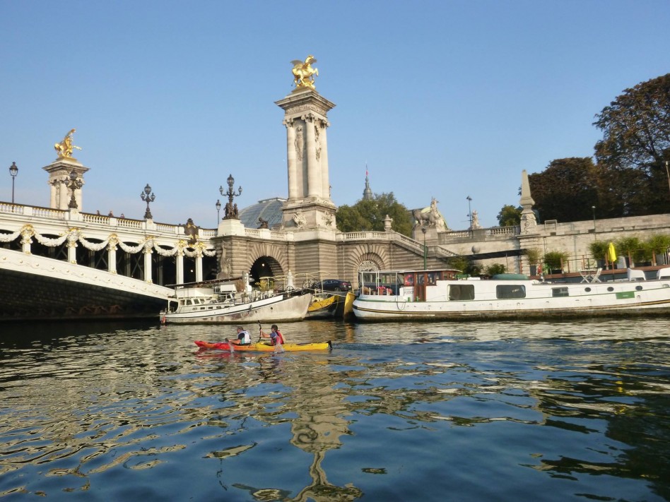 Des concurrents passent en kayak sous un pont de Paris